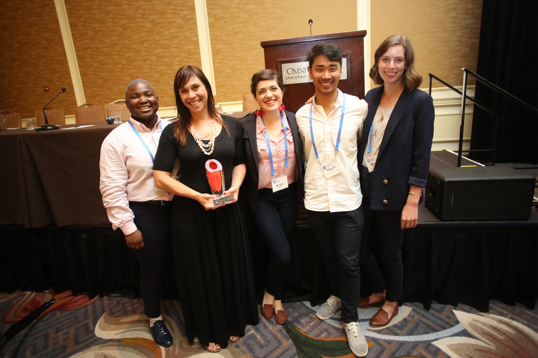 Students and Professor Roth smile with their award